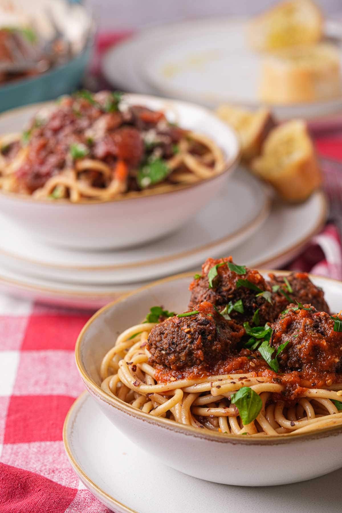Two bowls of spaghetti with vegan meatballs on a table.