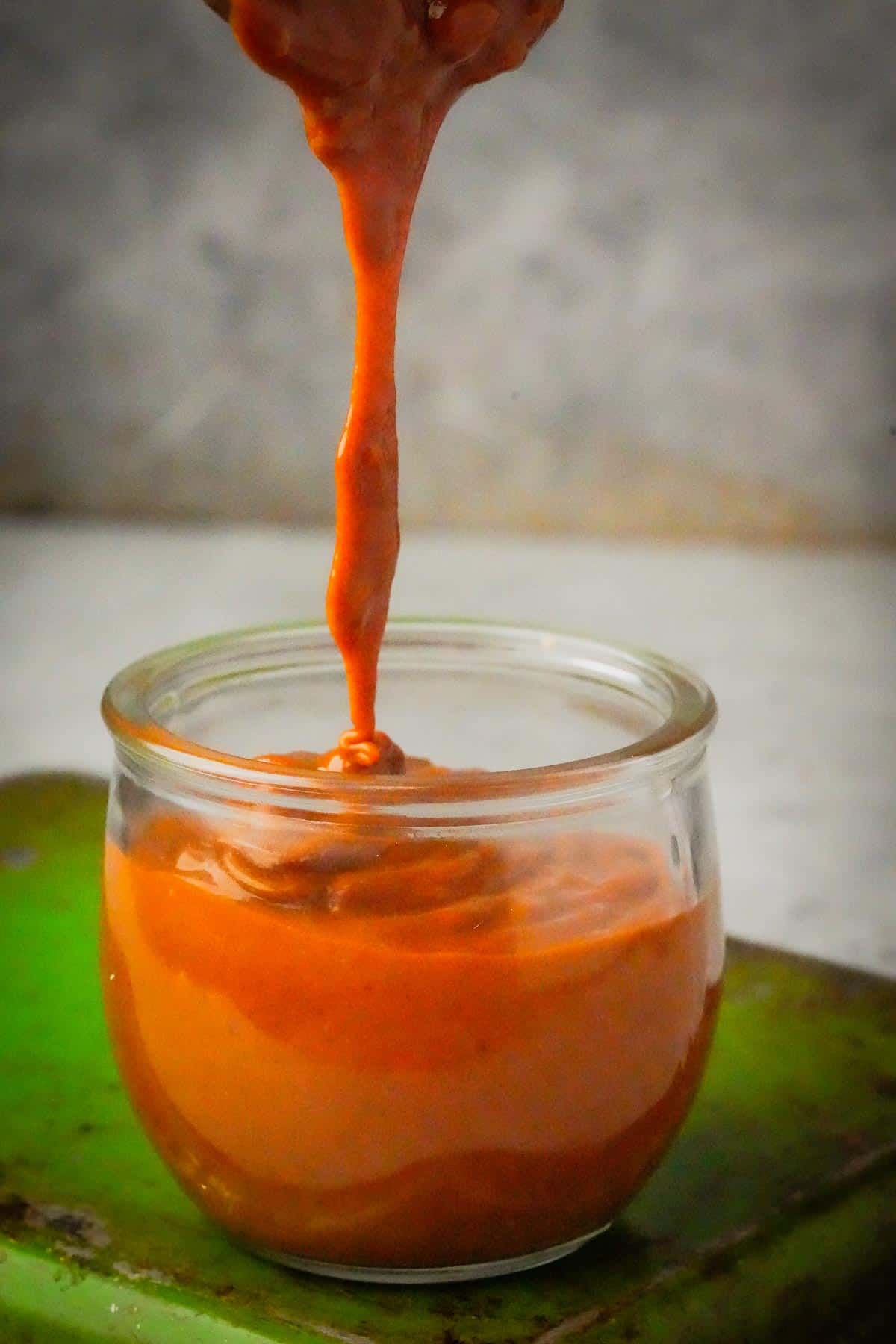 A person pouring Vietnamese Peanut Sauce into a bowl.