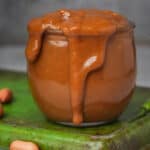 An overflowing jar of Vietnamese peanut sauce on a green tray.