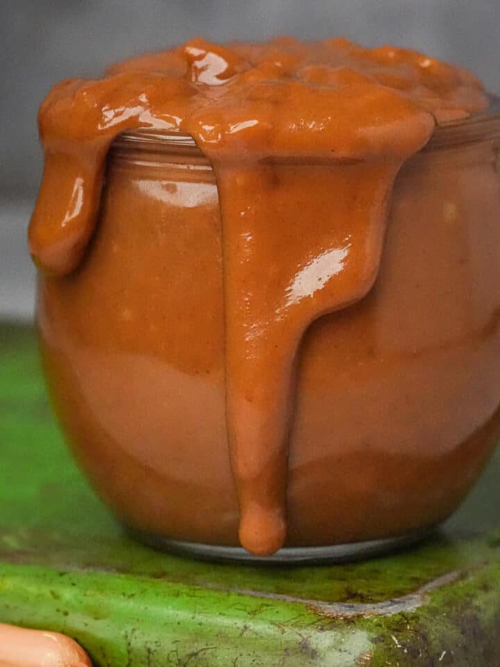 An overflowing jar of Vietnamese peanut sauce on a green tray.
