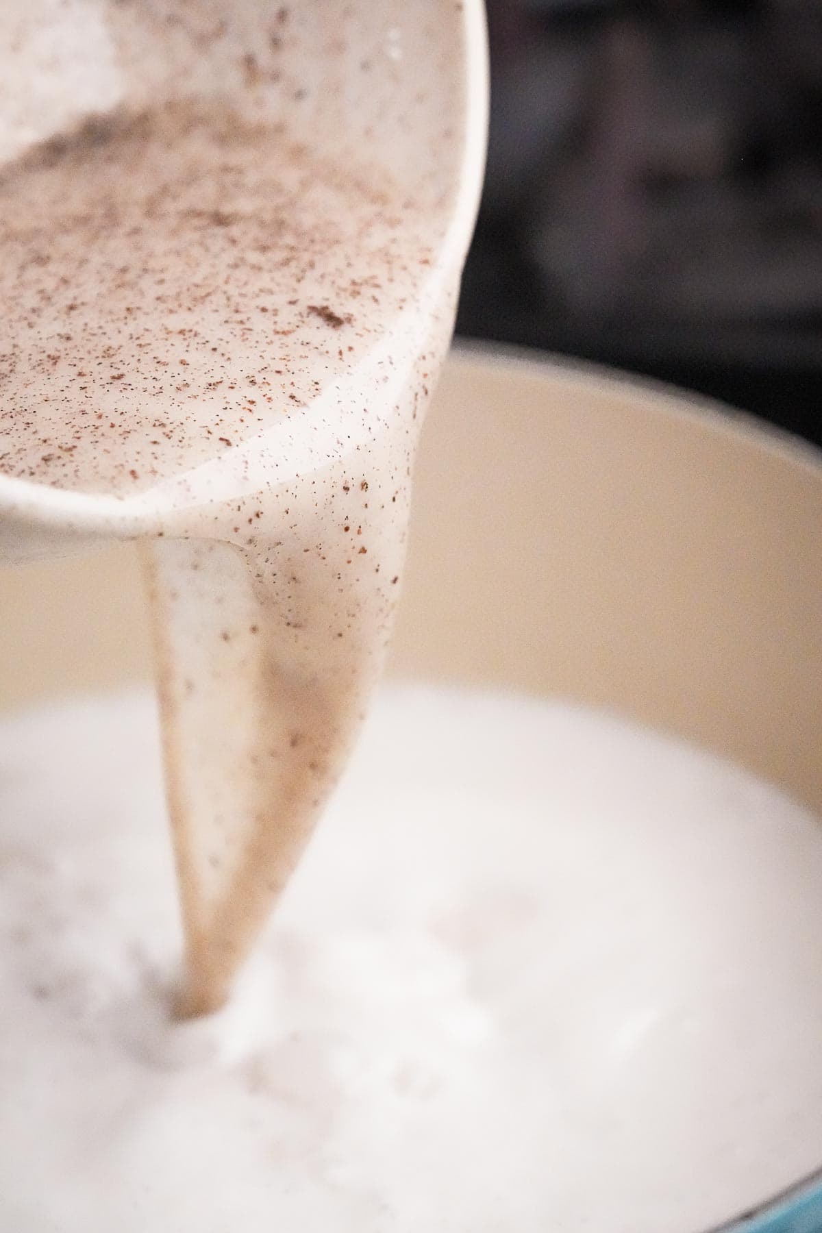 A person is pouring milk into a pan.