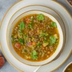 A bowl of Mexican lentil soup on a plate.