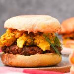 A close up of a breakfast sandwich with a smoked vegan breakfast sausage and scrambled tofu.