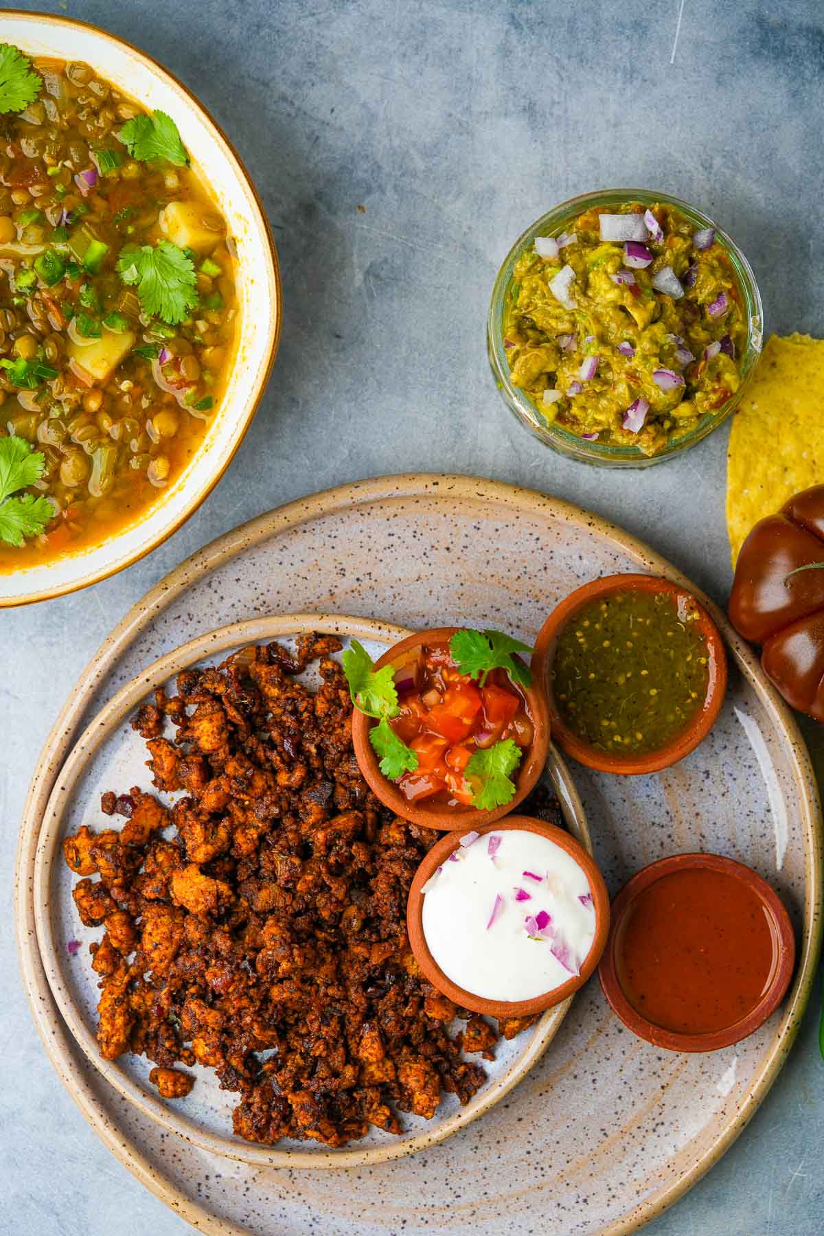 A plate of vegan chorizo on a table with guacamole and Mexican lentil soup.