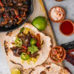 Vegan fajitas made with mushrooms on a wooden cutting board.