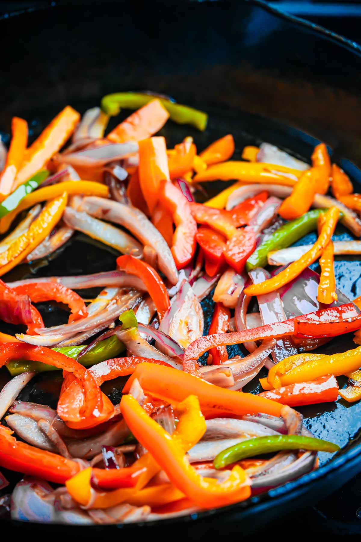A frying pan with onions and peppers in it.