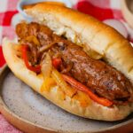 An Italian sausage sandwich with fried peppers and onions on a plate.