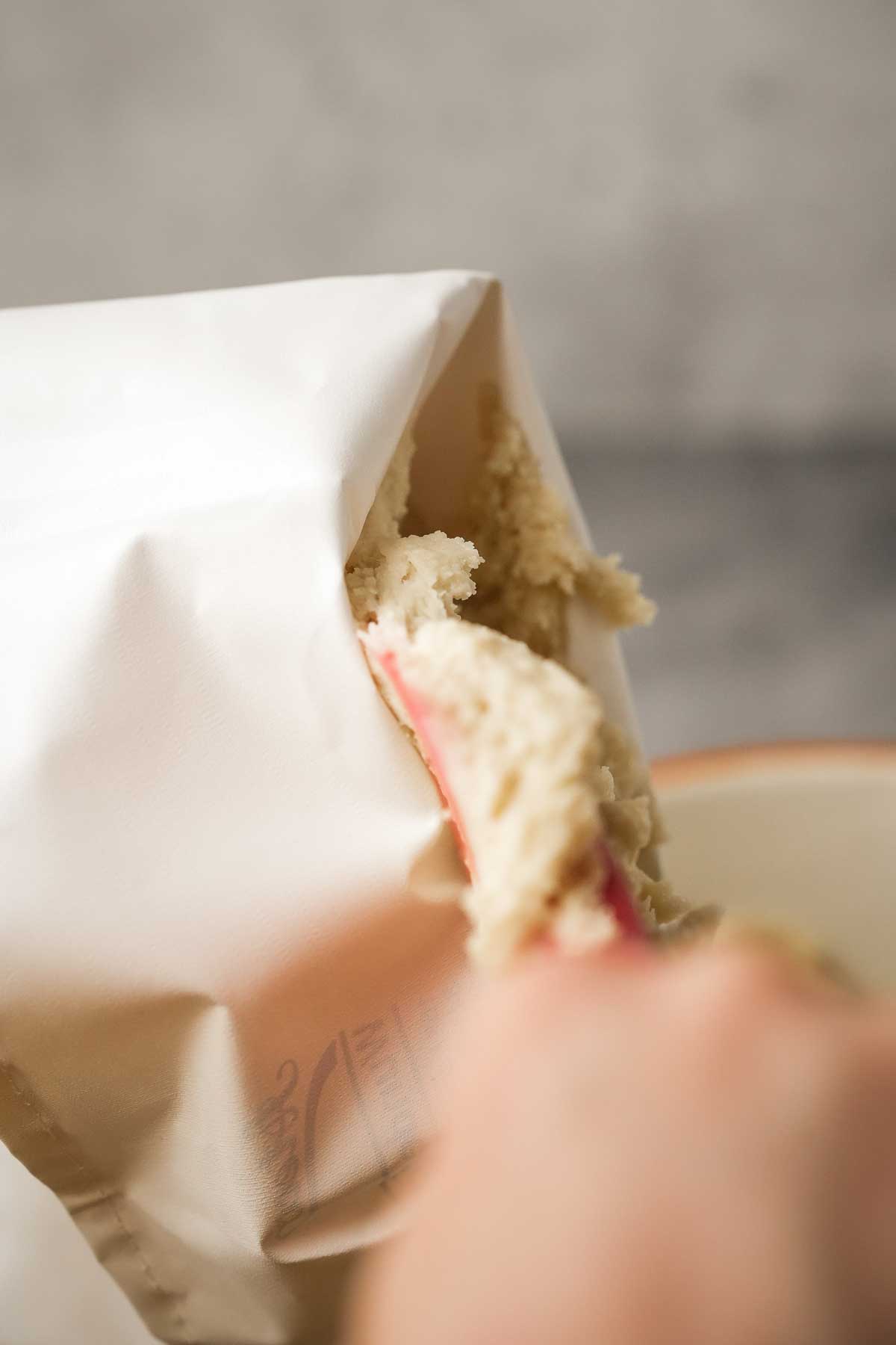 Loading vegan ladyfinger dough into a pastry bag.
