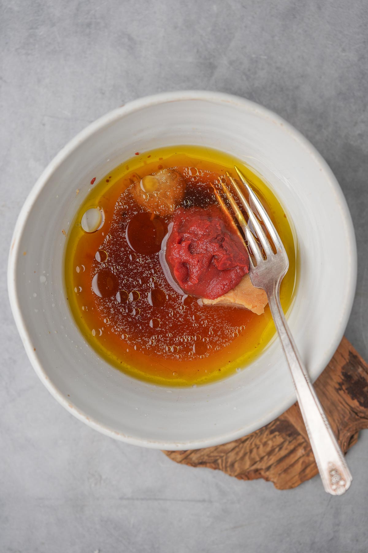 A white bowl with sauce and a fork.