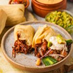 Vegan tamales on a plate with guacamole and guacamole.