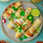 Mexican Vegan Taquitos on a plate with sauce and radishes.