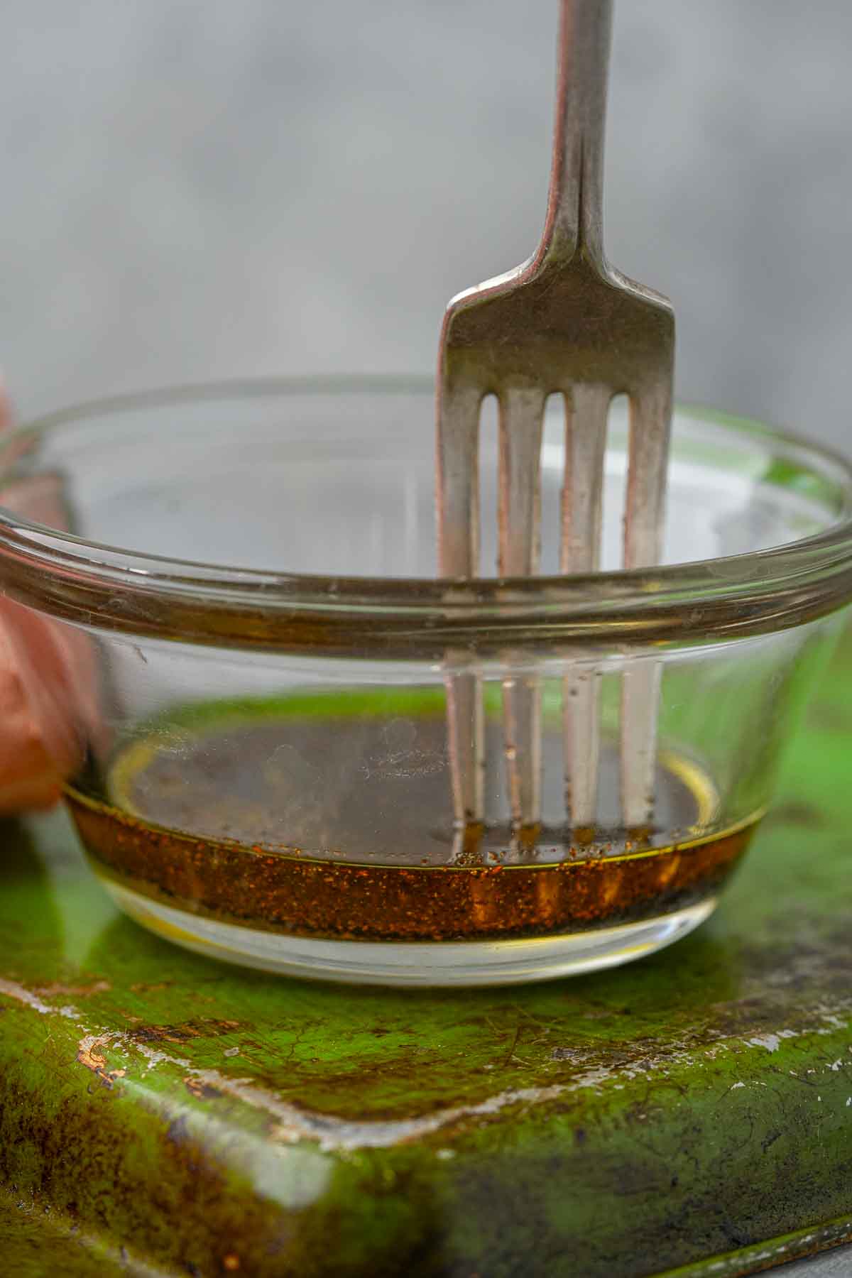 A person mixing seasoned oil in a bowl.