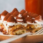 A piece of vegan tiramisu with a fork on a plate.