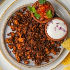 A plate of vegan chorizo with chips and salsa on it.