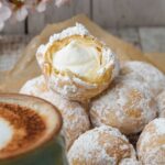 Cream-filled Zeppole dusted with powdered sugar on a table.