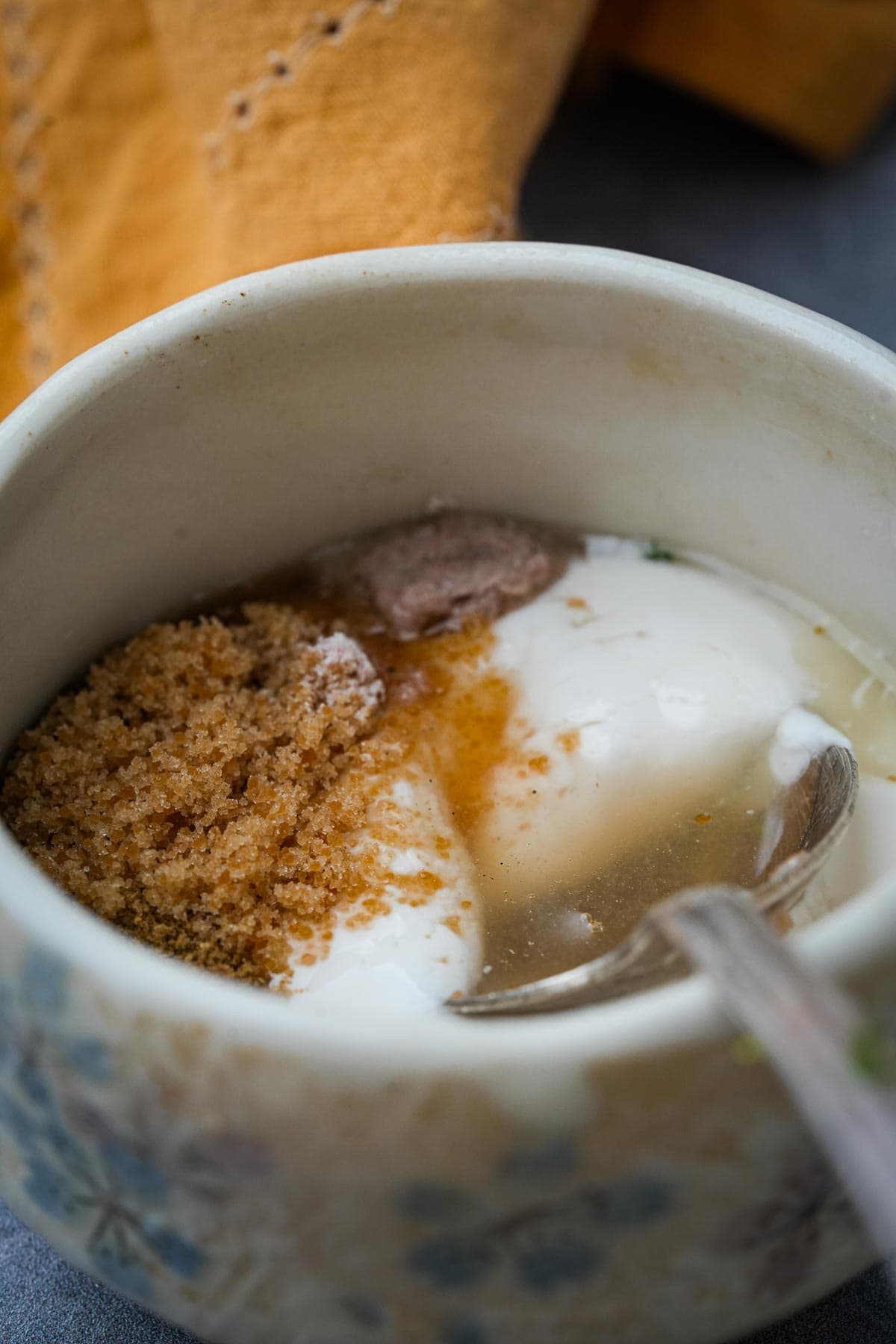 Yogurt being seasoned and mixed a ceramic bowl.