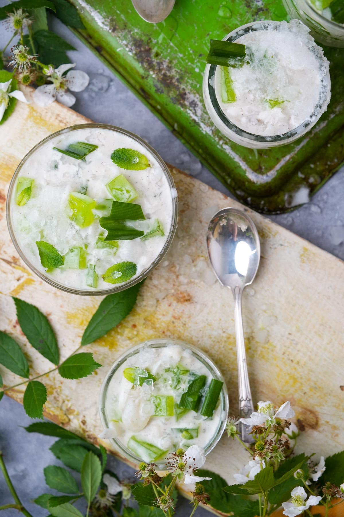 Three glass bowls filled with creamy Buko Pandan garnished with pandan leaves and mint.
