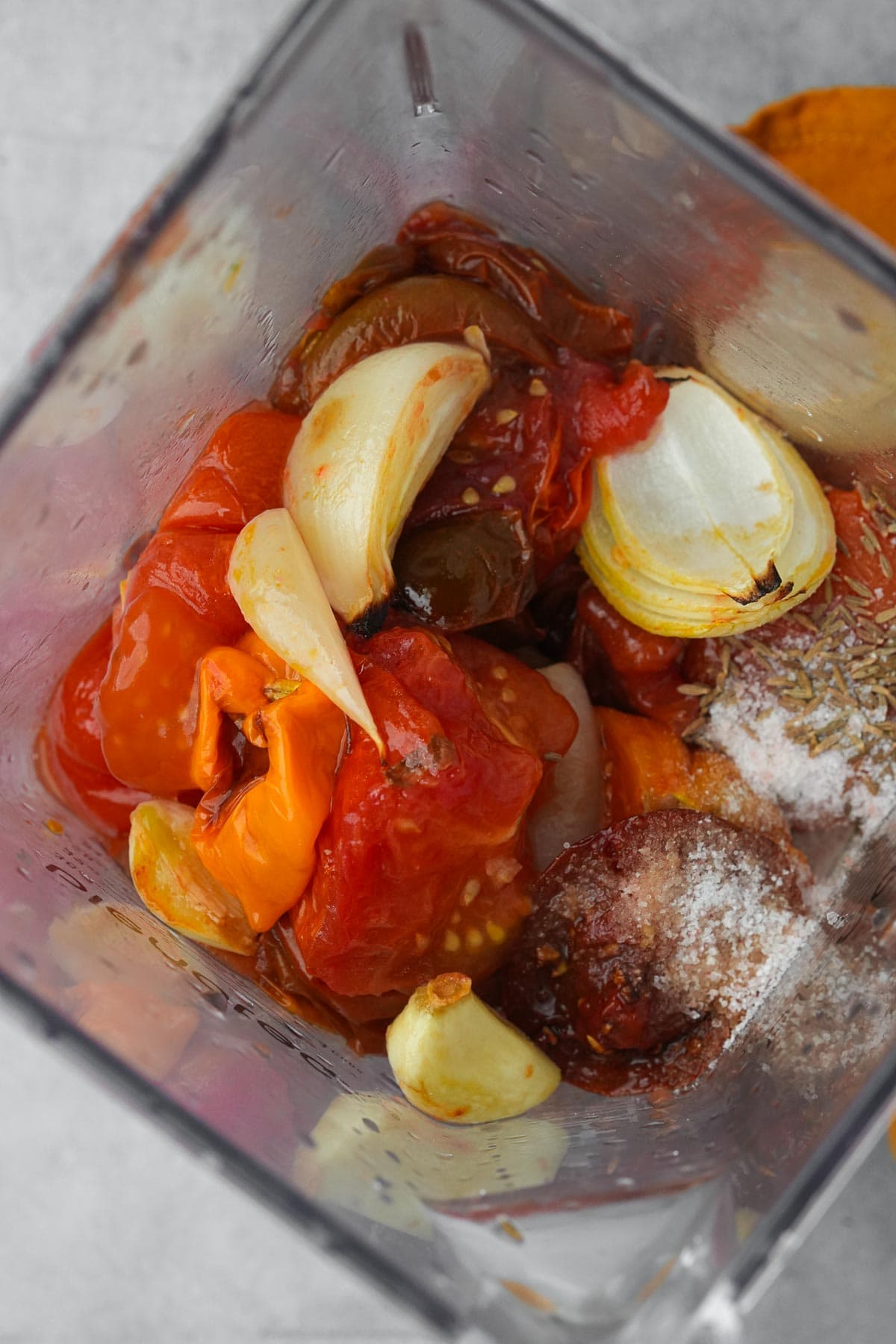 Ingredients for roasted habanero salsa in a blender, including whole garlic cloves, roasted peppers, and spices.