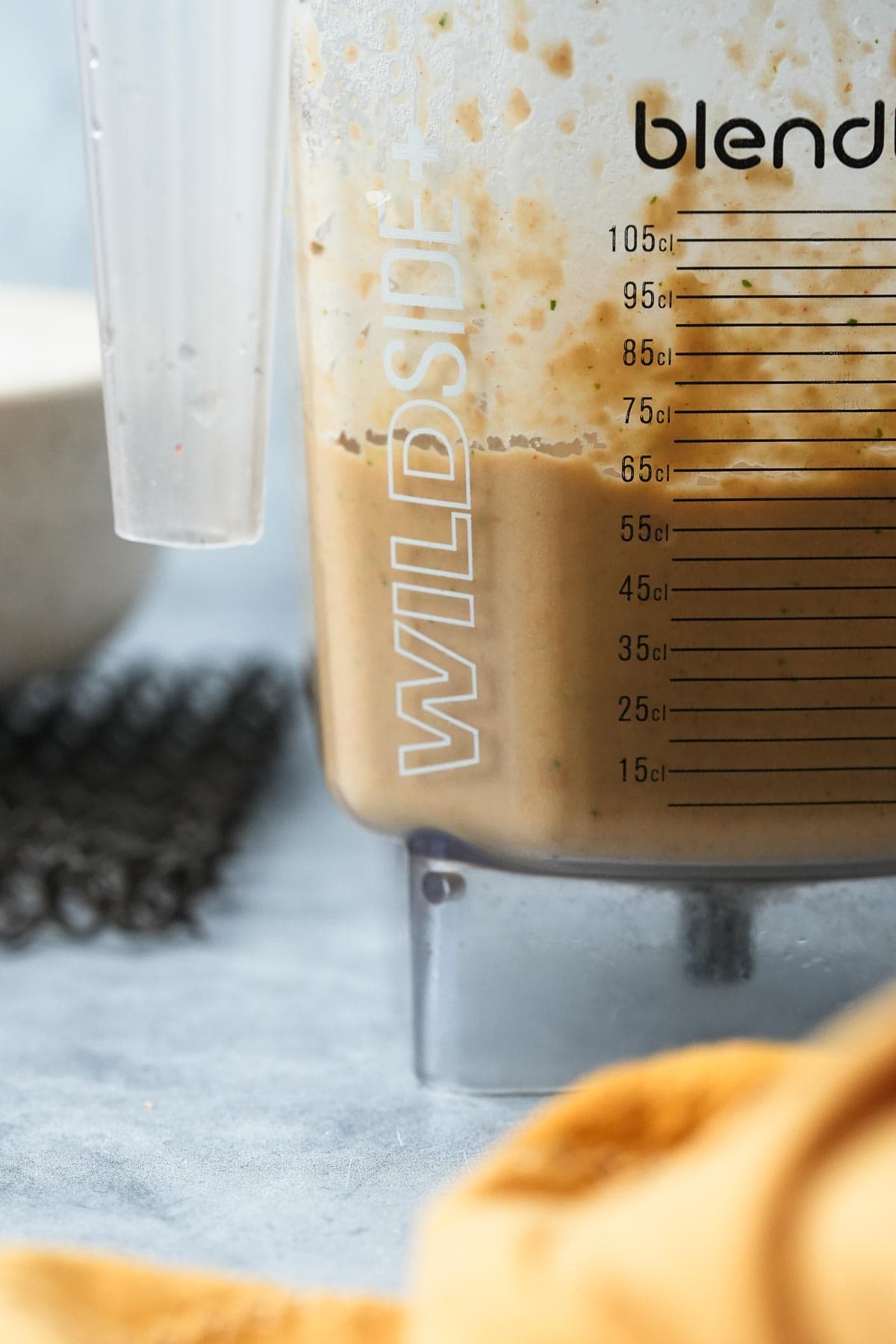 Close-up of a blender jug with pureed vegan refried beans, marked with measurements.