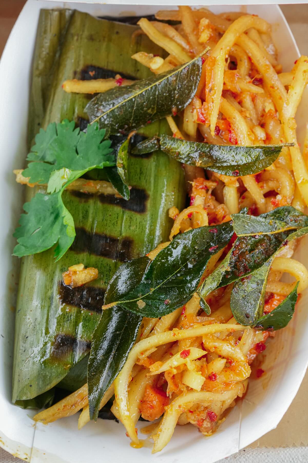 Lontong that's been grilled served with fried curry leaves and pickled achara.