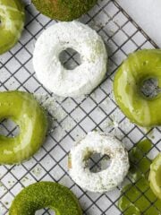 Vegan matcha donuts with assorted toppings on a cooling rack.