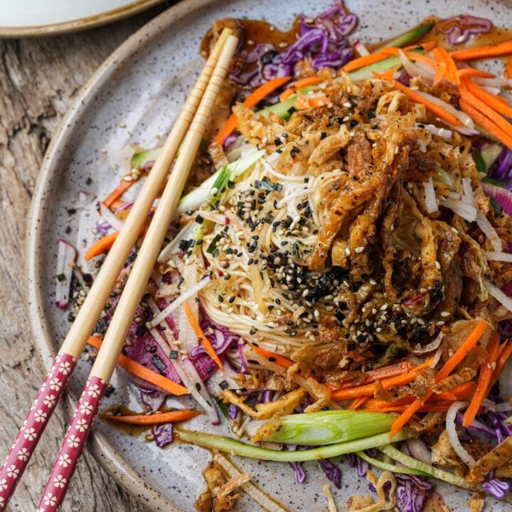 A plate of somen salad with shredded vegetables, sesame seeds, and chopsticks on the side.