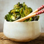 A bowl of sunomono salad garnished with sesame seeds and a pair of chopsticks resting on the bowl.