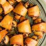 Golden-brown, glazed vegan rugelach filled with a dark chocolate filling, arranged on a round green wire rack.