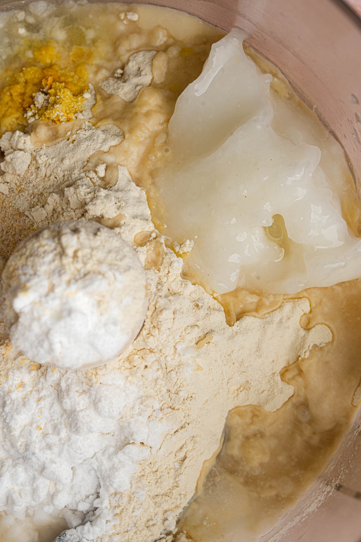 Close-up of ingredients in a food processor, including vital wheat gluten, nutritional yeast, coconut oil, water, and seasonings before being mixed together to make seitan bacon fat.
