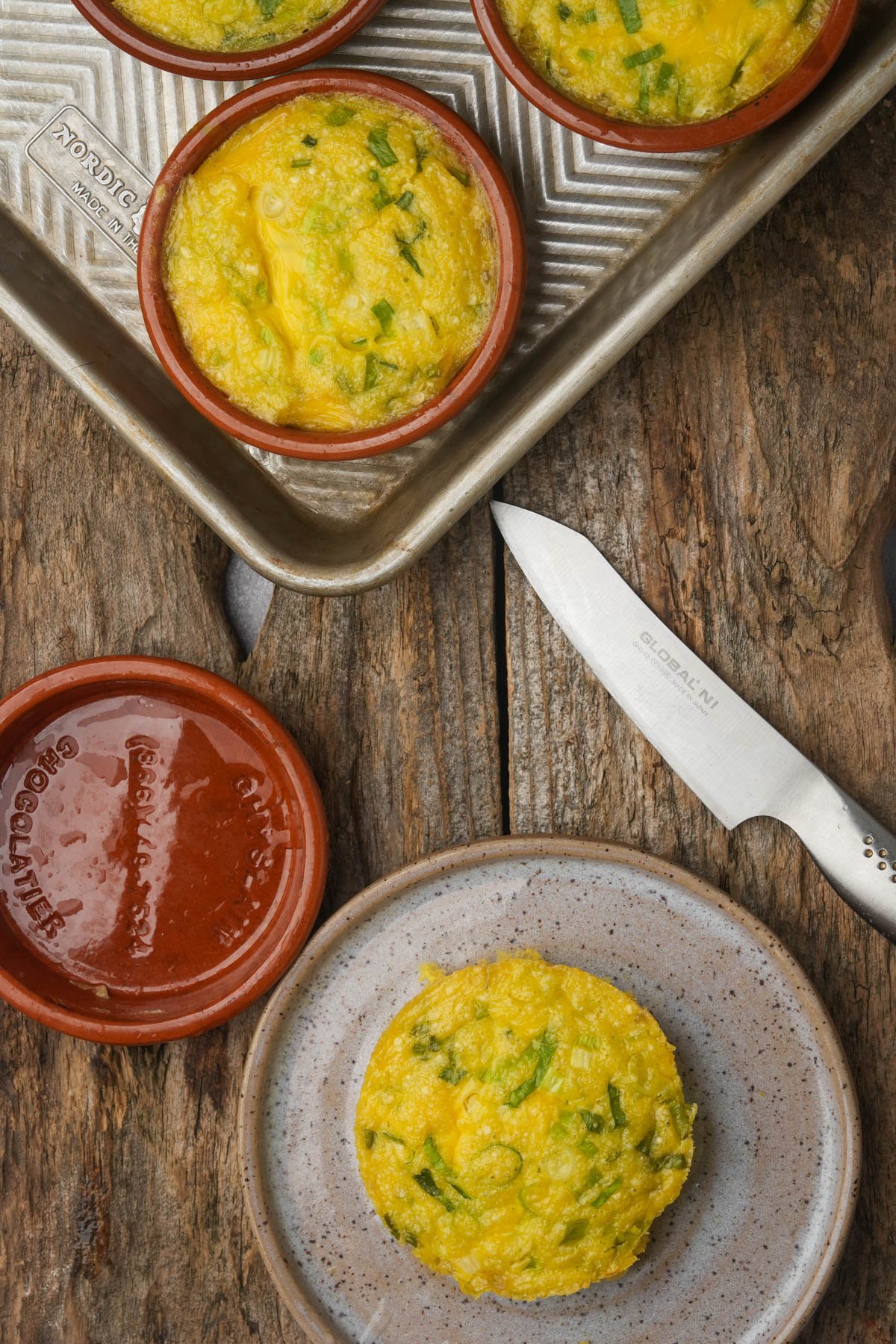 A baked Just Egg patty with chopped green scallions is removed from the mold onto a plate.