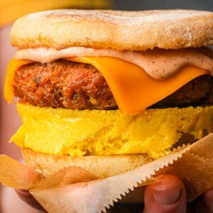 A vegan breakfast sandwich with a veggie patty, melted cheddar cheese, Just Egg, chipotle mayo, and an English muffin.