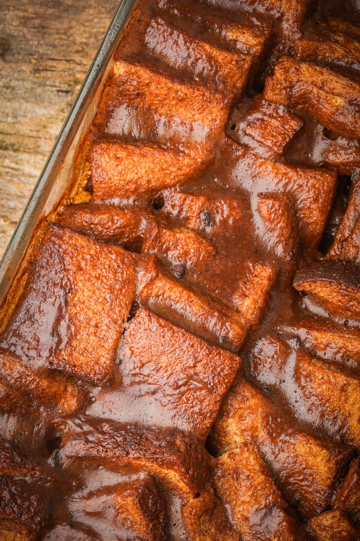 A baked vegan French toast casserole in a rectangular glass pan on a wooden surface.