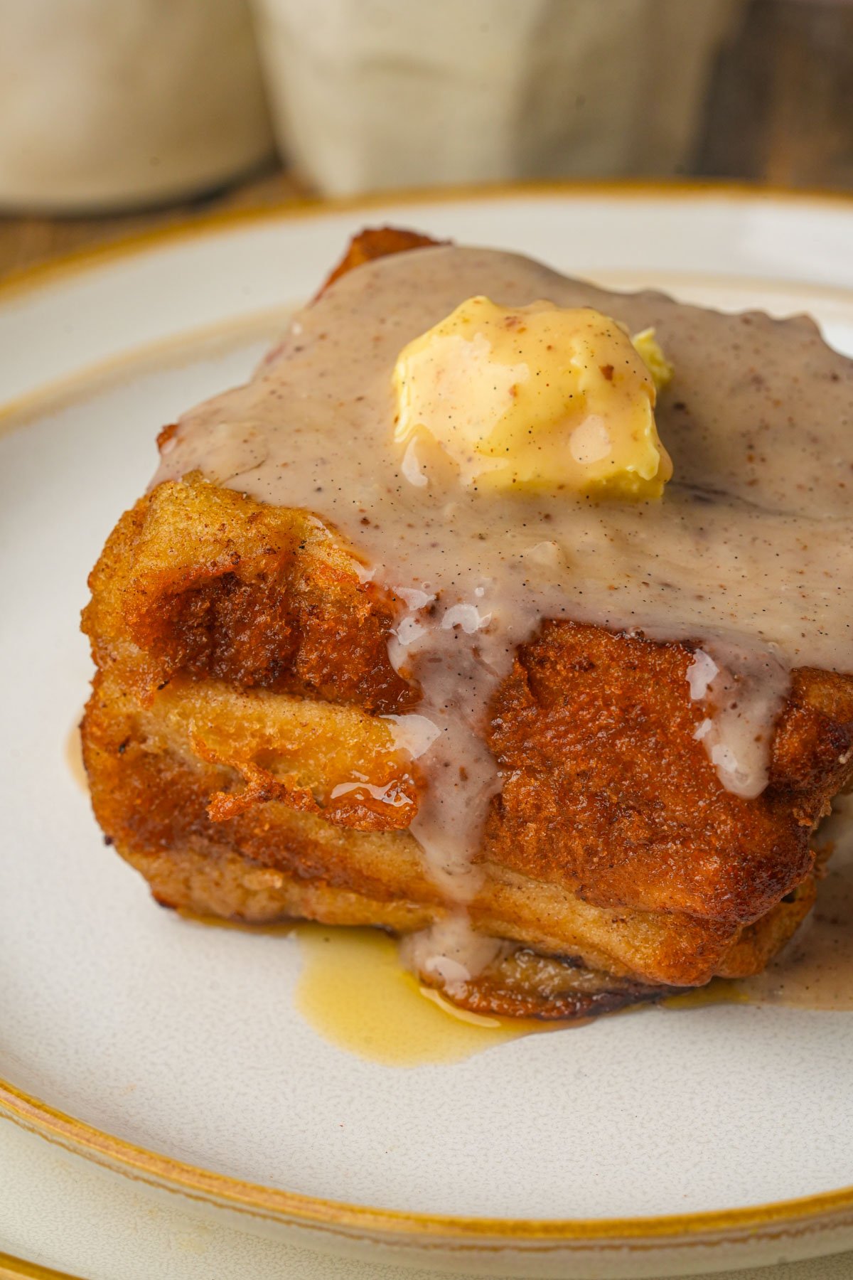 A slice of Hong Kong french toast topped with melted butter and a drizzle of condensed coconut milk sauce on a white plate.