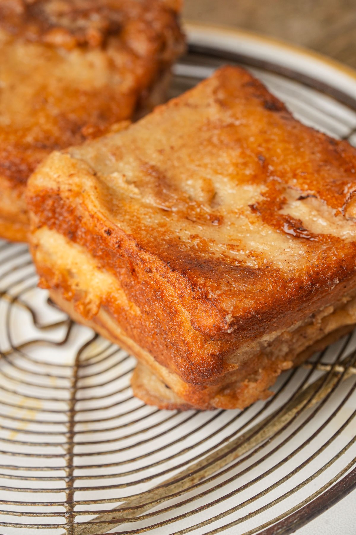 Two square pieces of golden-brown Hong Kong french toast are placed on a patterned plate.