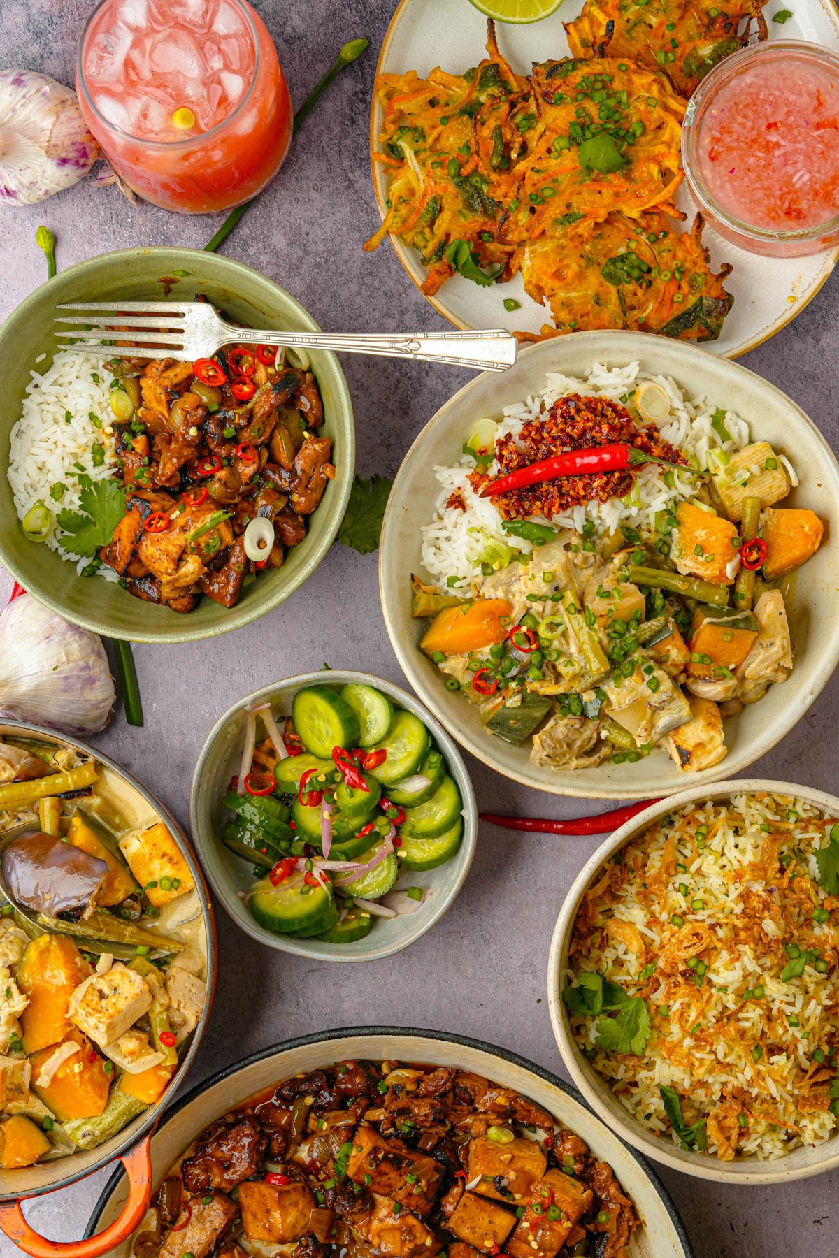 A table with bowls of Filipino food including sinangag, tokwat baboy, vegetable okoy, ginataang gulay, and ensaladang pipino.
