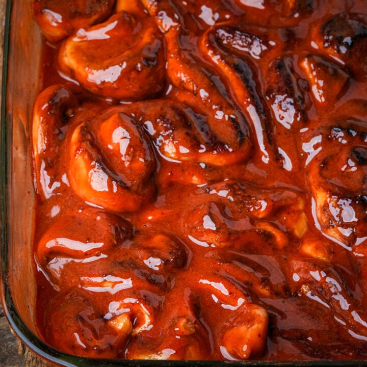 Vegan Halloween cinnamon roll guts covered in a thick, dark red berry glaze in a glass baking dish.