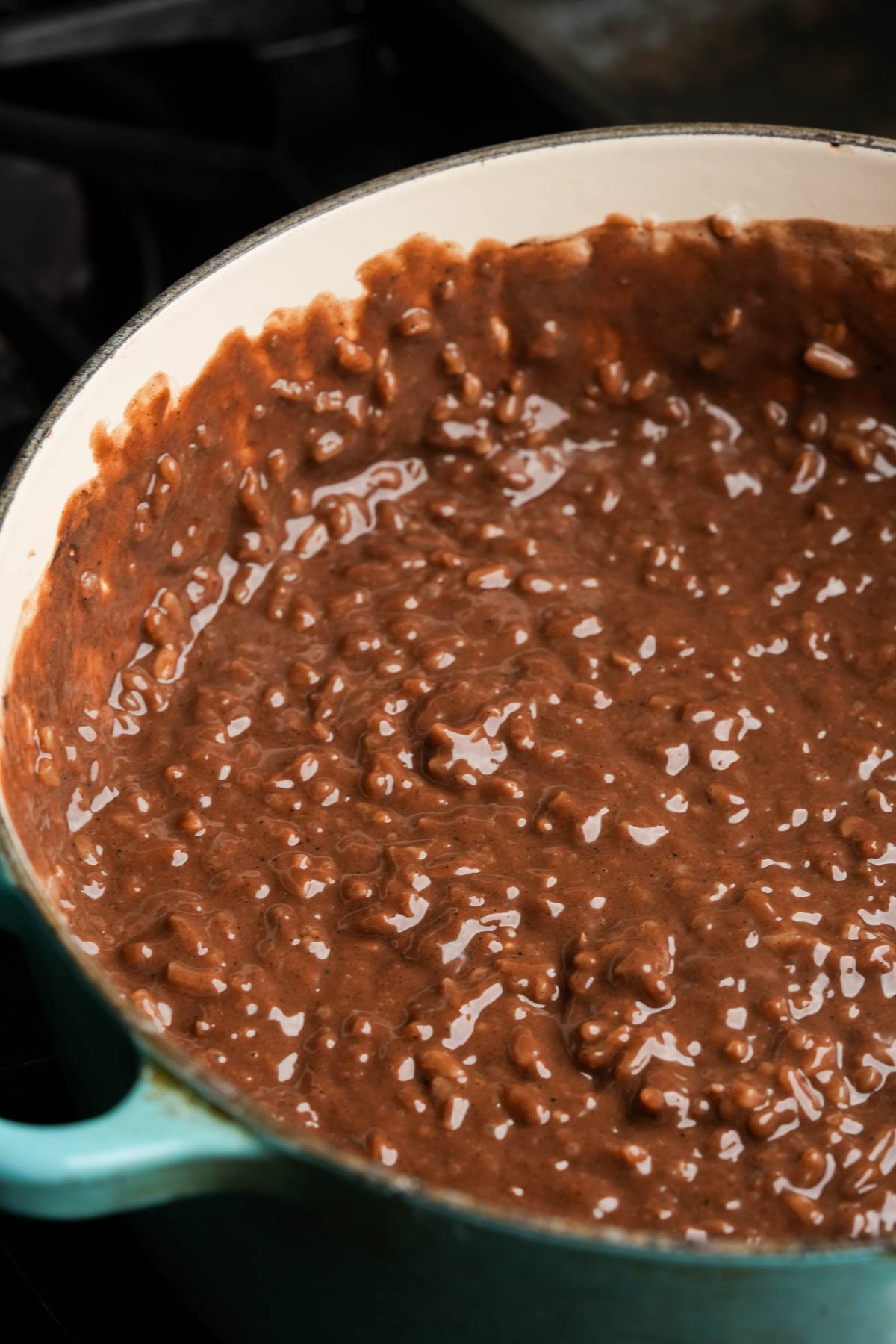 A close-up of a large pot filled with creamy vegan champorado, showing the thick, textured mixture with visible rice grains.