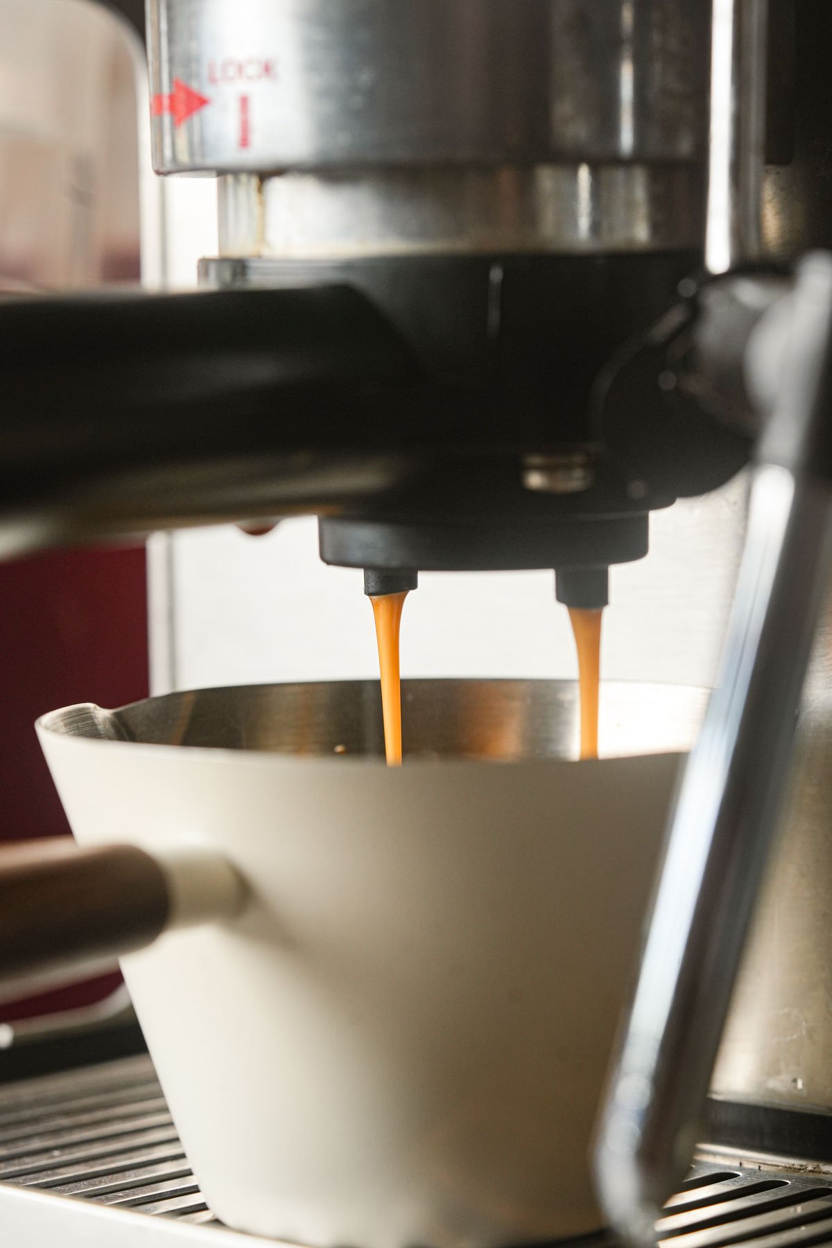 An espresso machine brewing two streams of coffee into a white cup placed below the machines spouts.