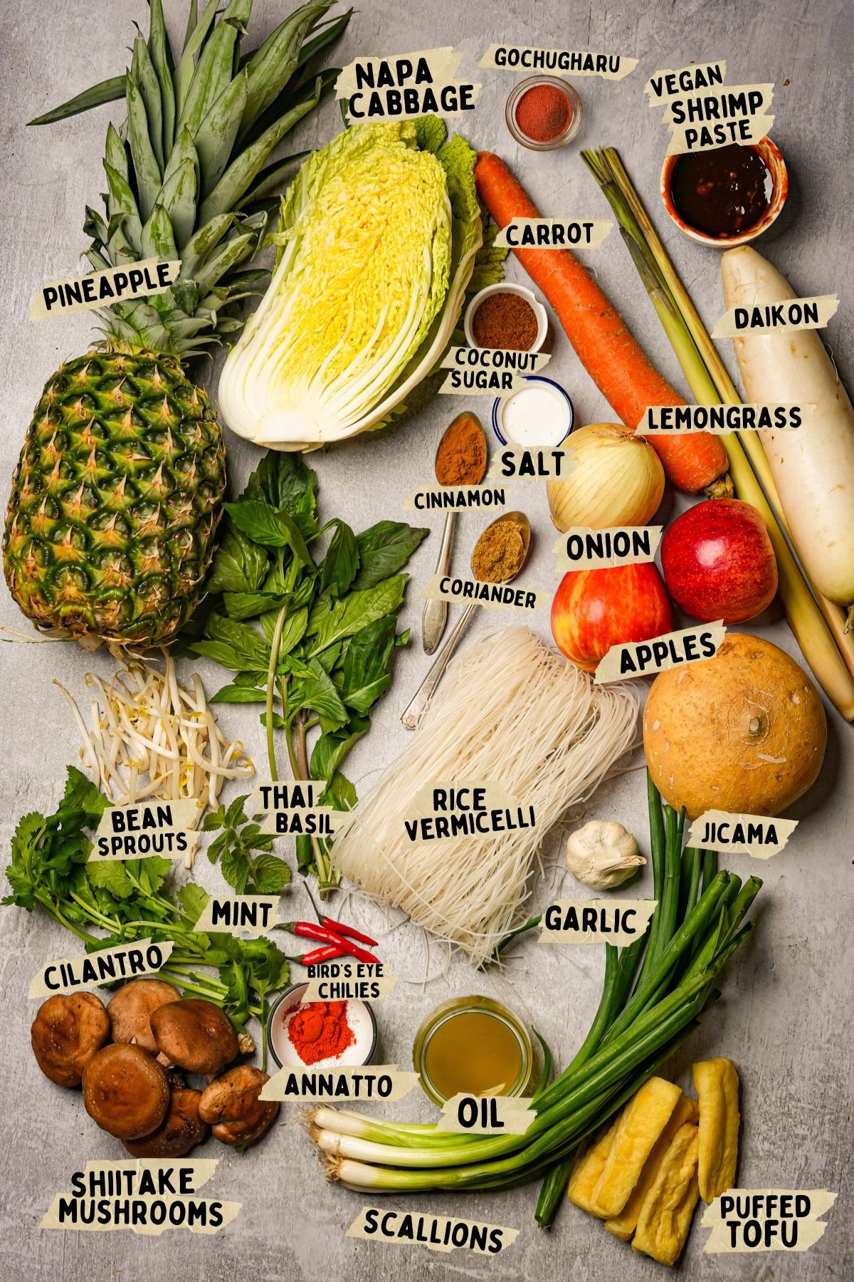 Ingredients labeled for a vegan bun bo hue recipe including pineapple, napa cabbage, carrot, daikon, jicama, mint, lemongrass, scallions, rice vermicelli, shiitake mushrooms, and seasonings.