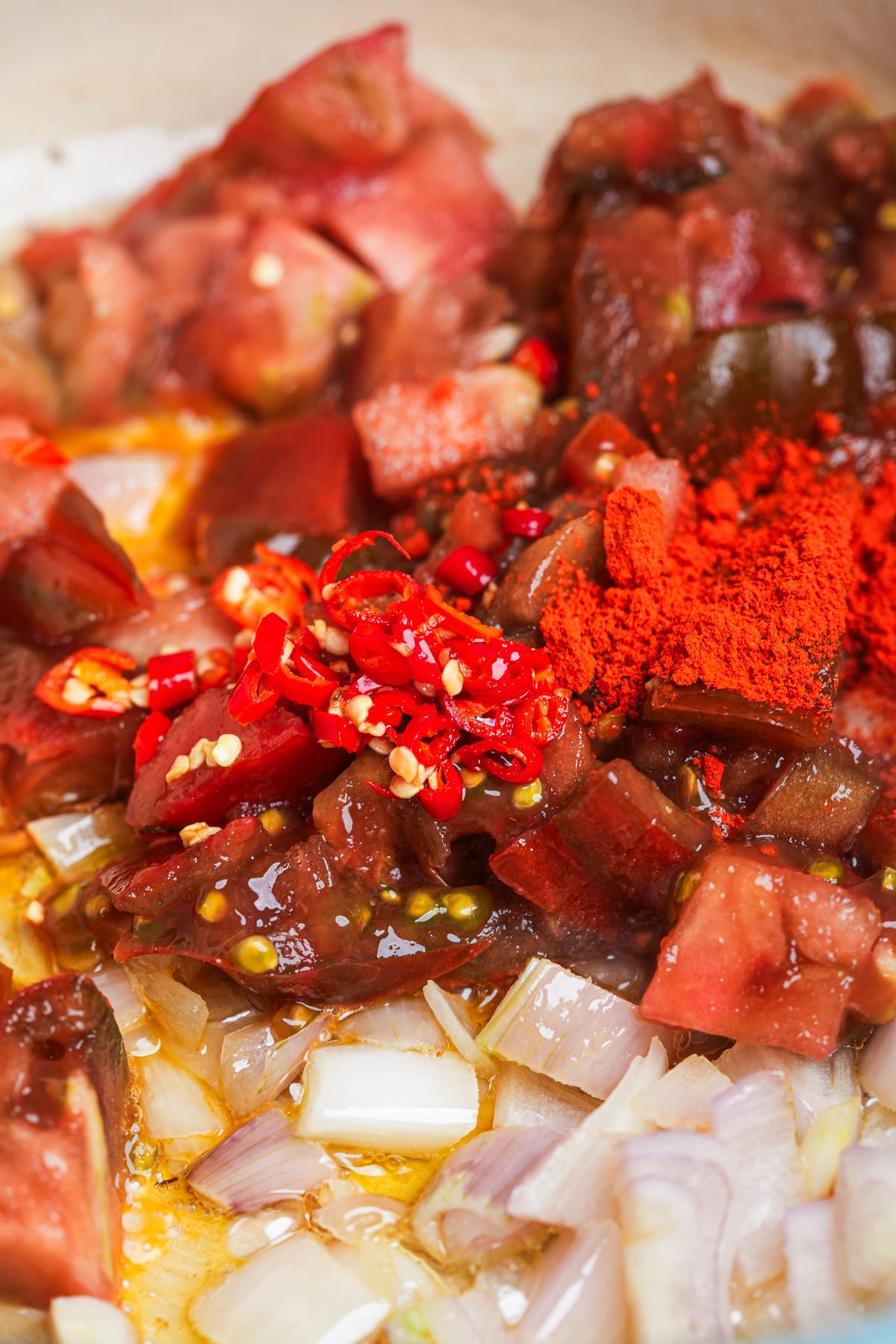 Chopped onions, tomatoes, and red chili peppers are mixed with oil and a heap of red annatto.