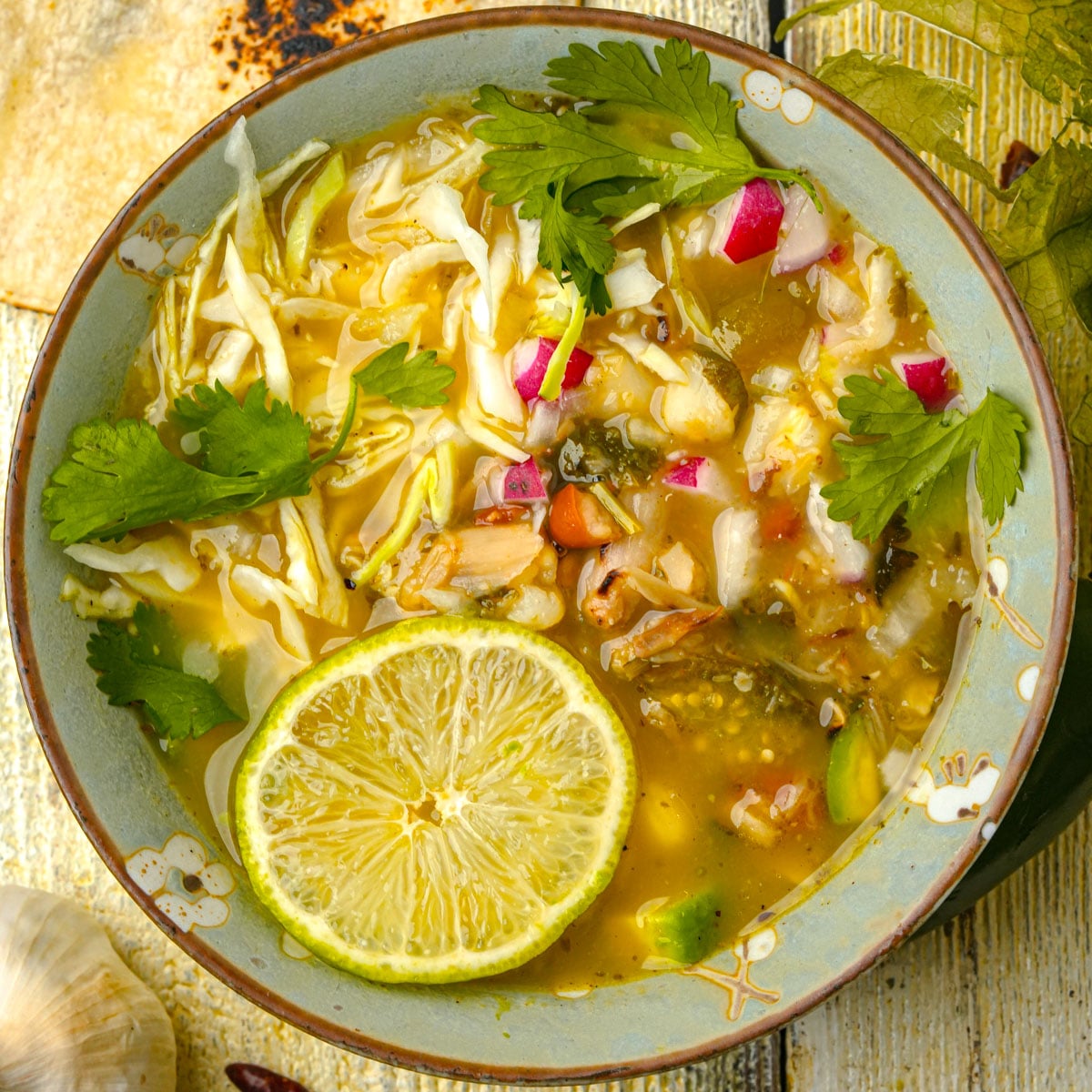 Bowl of vegan pozole verde with lime and radishes