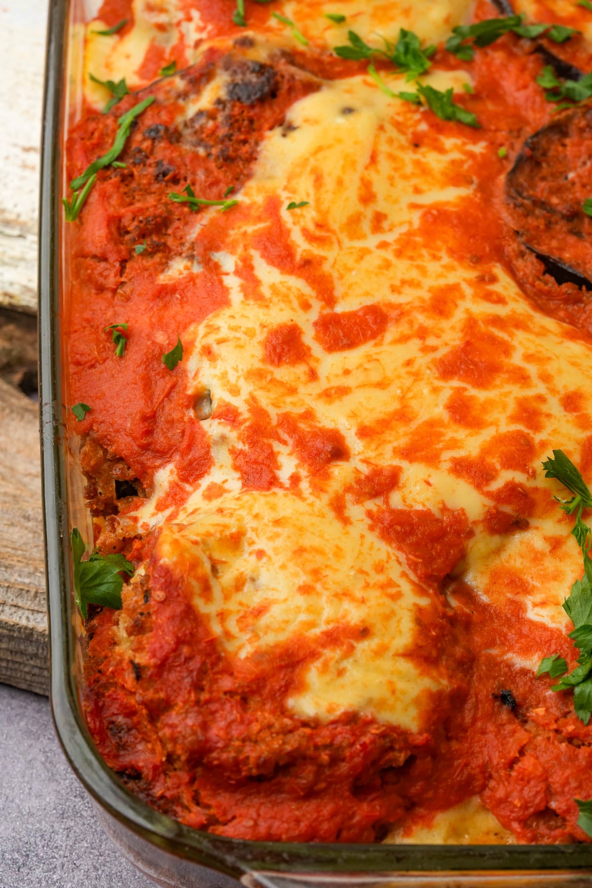 A baked vegan eggplant parm served in a glass casserole dish.