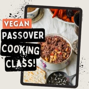 A bowl of charoset with chopped apples sits on a white tablecloth next to matzah, stewed dried fruits, a silver goblet, and a serving utensil. Overlaid text reads Vegan Passover Cooking Class!.