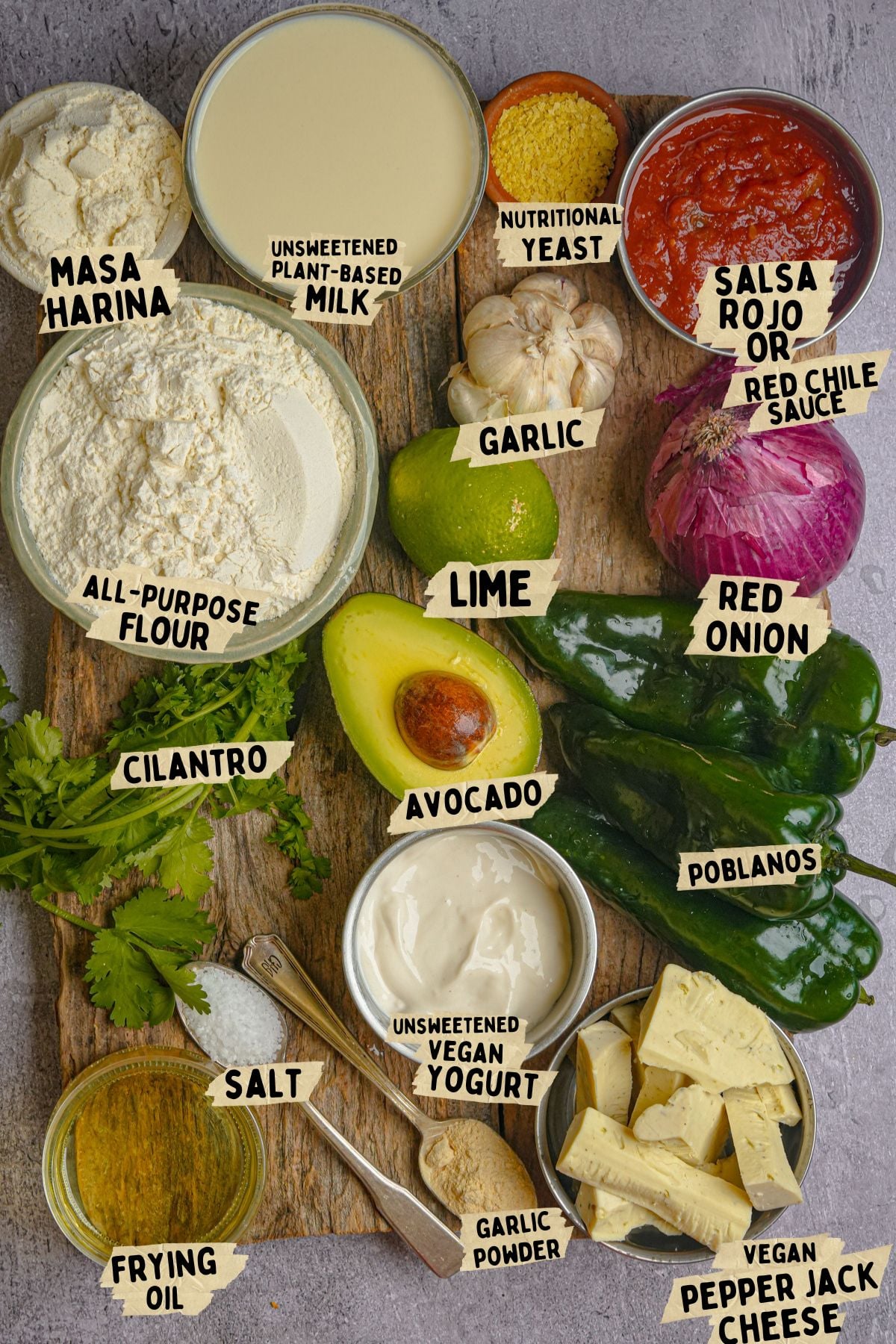 Labeled ingredients for a vegan chile rellano recipe, including masa harina, plant-based milk, nutritional yeast, salsa, flours, onion, poblanos, vegan cheese, yogurt, garlic, lime, avocado, cilantro, salt, and frying oil.