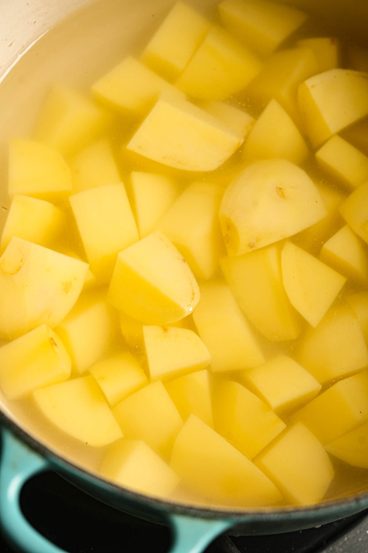 Cubed potatoes are submerged in water in a pot, ready to be boiled.