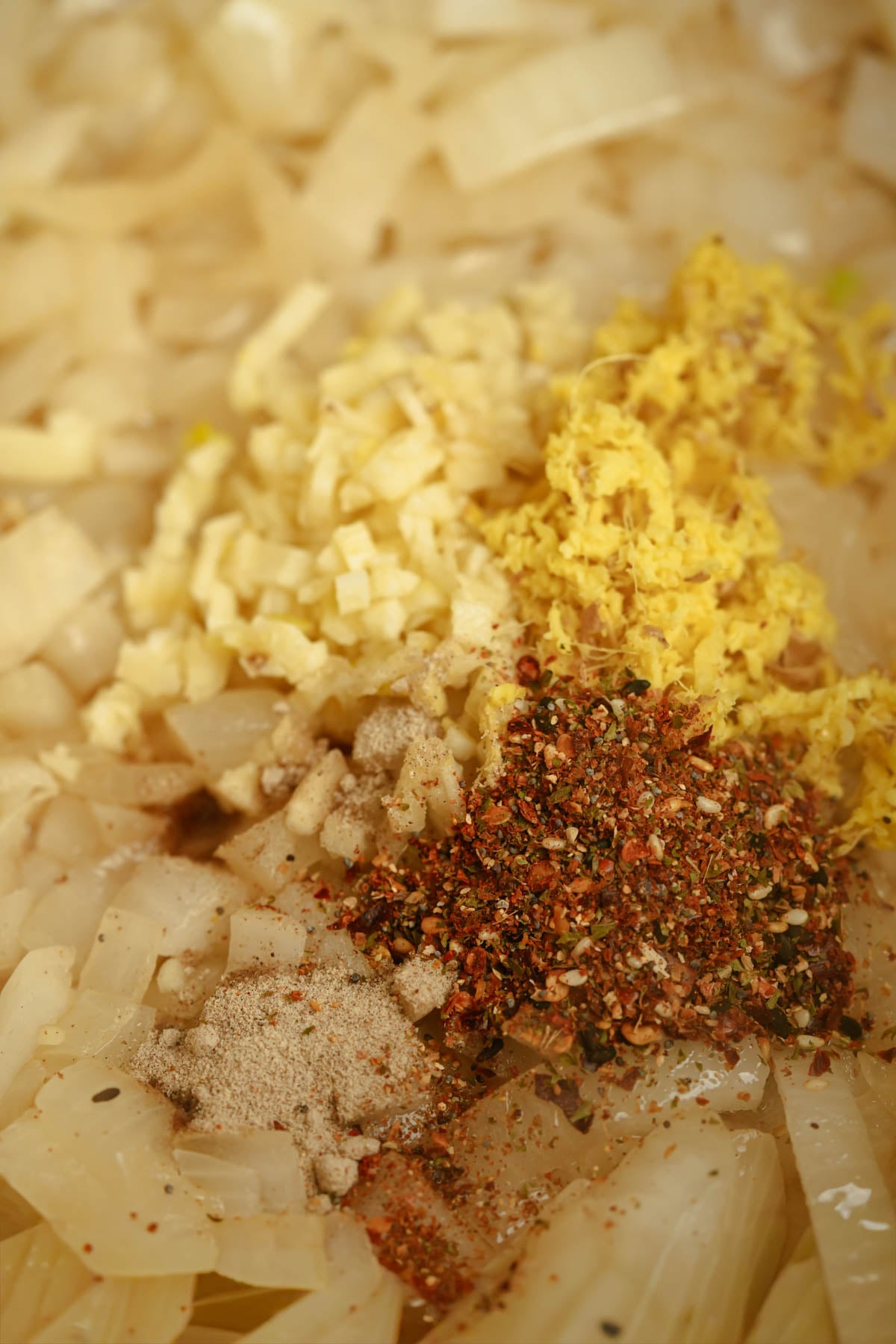 Chopped onions, minced garlic, grated ginger, white pepper, and togarashi being sautéed.