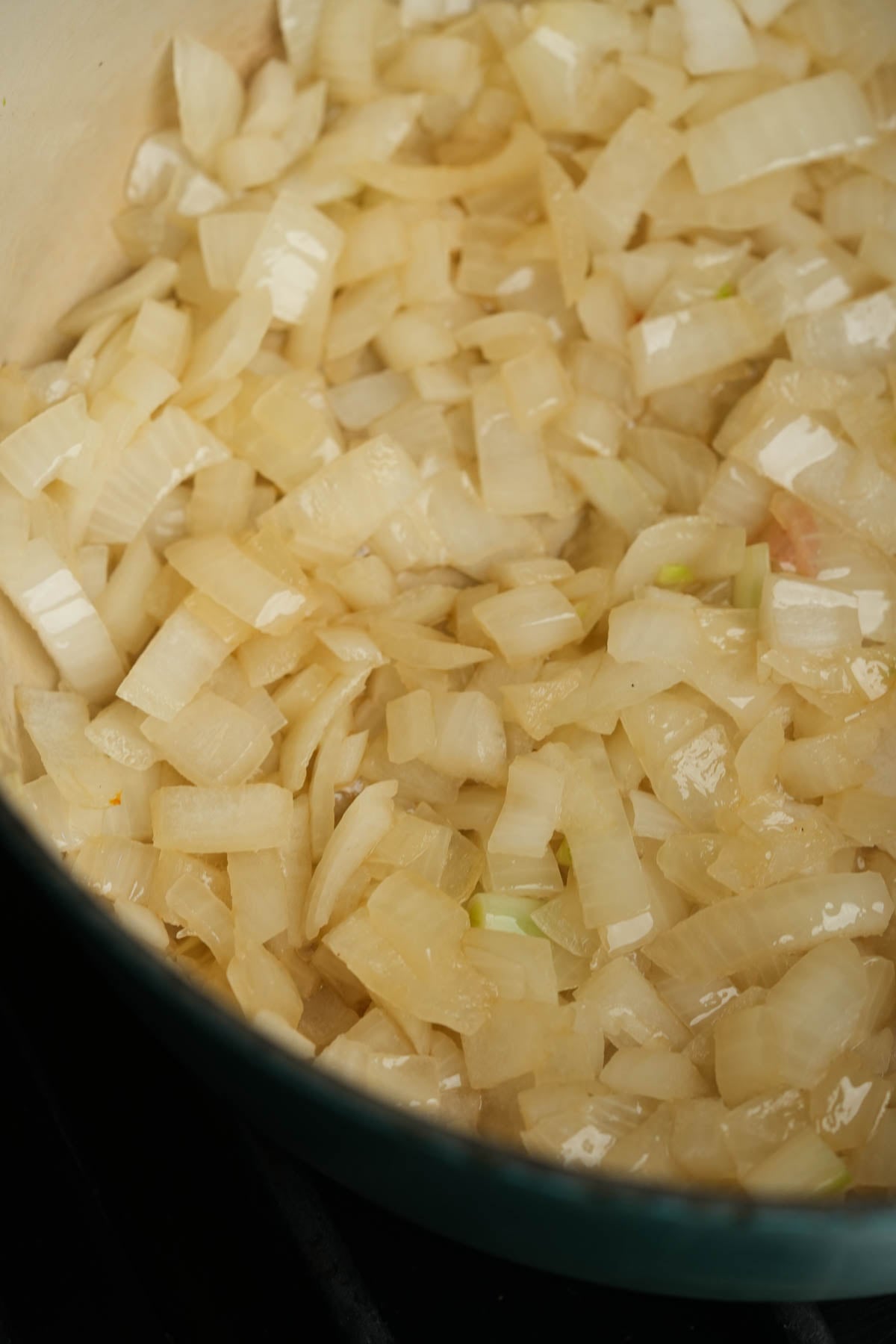 Chopped onions sautéing in a pan, turning translucent as they cook in oil or butter.