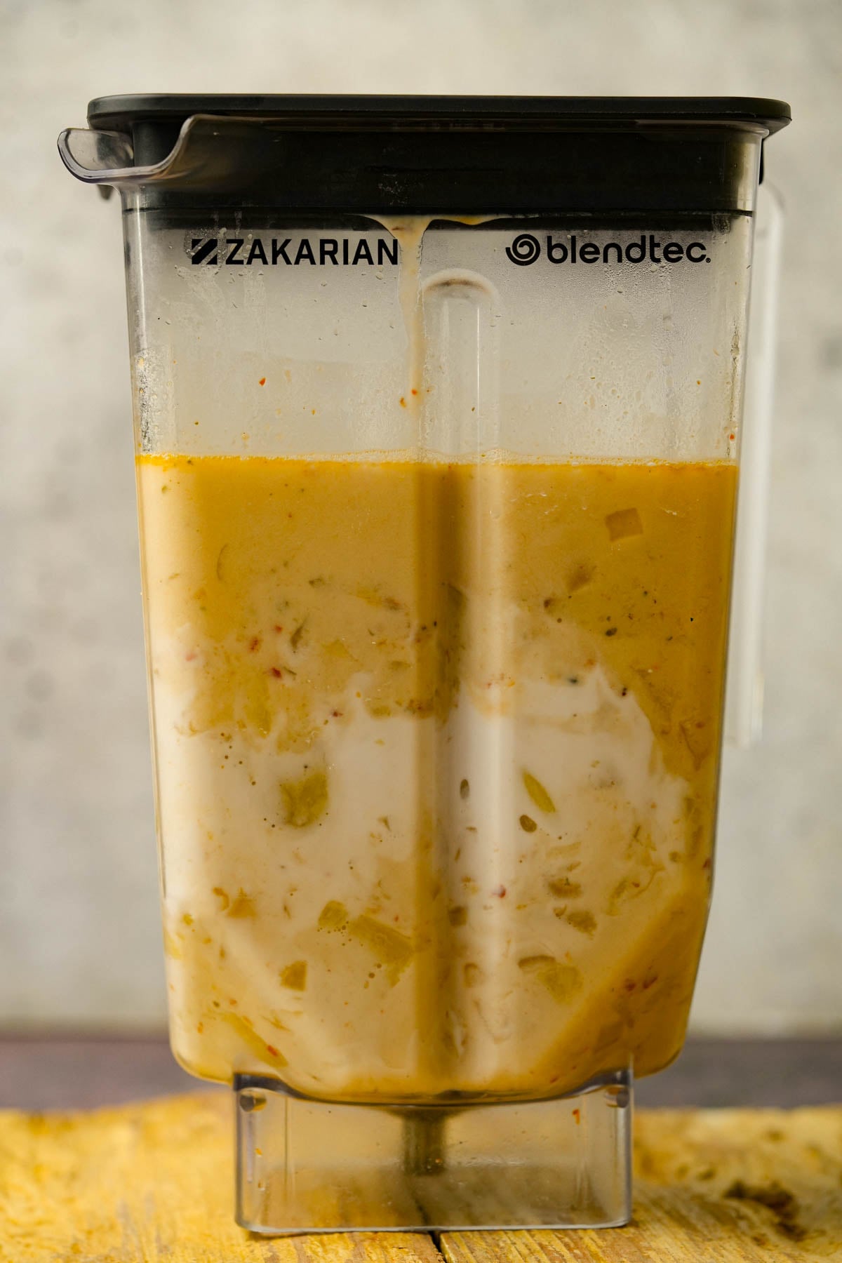 A blender jar filled with unblended Japanese sweet potato soup with visible chunks and swirls of white, placed on a wooden surface.