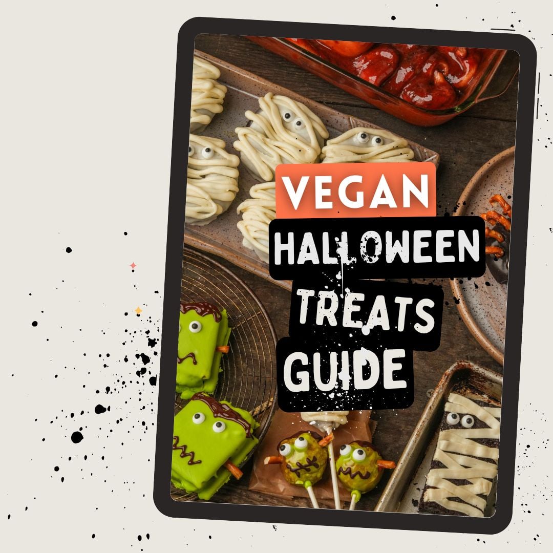 Tablet displaying Vegan Halloween Treats Guide with various spooky-themed vegan desserts like green monster pops, mummy cookies, and candied apples on a splattered background.
