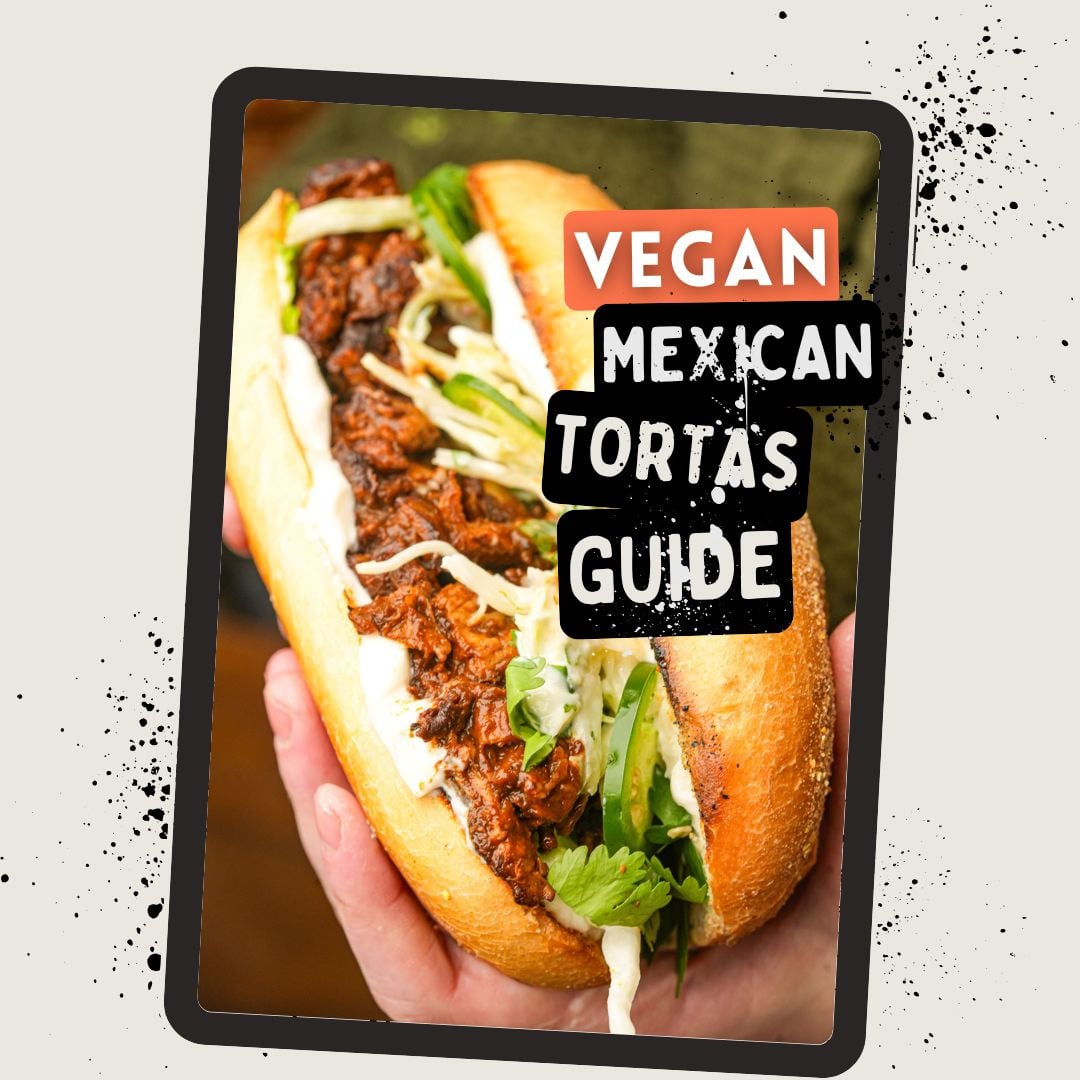 A person holds a Mexican torta sandwich filled with vegan meat, lettuce, and sauce. Text on the image reads: Vegan Mexican Tortas Guide..
